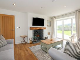 A living room with sofas coffee table fireplace and sliding glass doors overlooking a garden at Criw in Bryncroes near Sarn Meyllteyrn