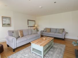 A living room with two gray sofas a wooden coffee table and a rug at Criw in Bryncroes near Sarn Meyllteyrn
