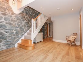 A hallway with wooden flooring stone wall staircase and a wicker chair at Criw Bryncroes near Sarn Meyllteyrn