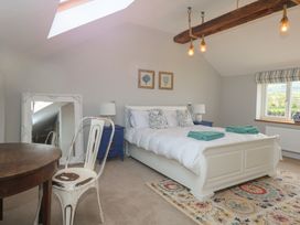 A bedroom with a white bed and blue bedside tables near a window at Criw in Bryncroes near Sarn Meyllteyrn