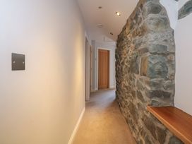 A corridor with a stone wall on the right and doors at the end at Criw in Bryncroes near Sarn Meyllteyrn