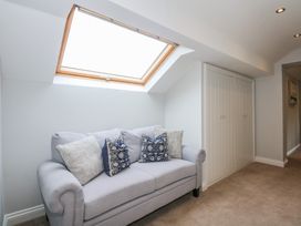 A seating area with a light grey sofa and patterned cushions under a skylight window at Criw in Bryncroes near Sarn Meyllteyrn
