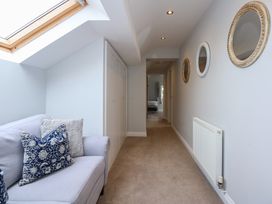 A hallway with a skylight window a sofa with cushions built in cupboards round mirrors on the wall and a radiator at Criw in Bryncroes near Sarn Meyllteyrn