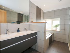 A bathroom with a double sink vanity and a bathtub next to a window with a plant at Criw in Bryncroes near Sarn Meyllteyrn