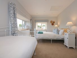 A bedroom with two beds a nightstand lamps and patterned curtains at Criw in Bryncroes near Sarn Meyllteyrn