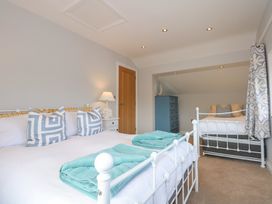 A bedroom with two white metal beds a blue chest of drawers and a wooden door at Criw in Bryncroes near Sarn Meyllteyrn