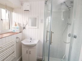 A bathroom with a shower, sink, and storage at 8 Rogeston Cottages Haverfordwest