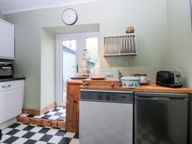 A kitchen with a clock and various appliances at Pen Glorian in Conwy