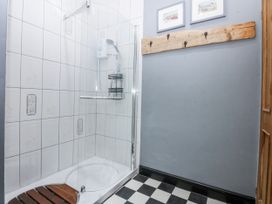 A bathroom with a shower and wooden shelf at Pen Glorian in Conwy