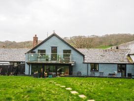 A house with a deck and sliding doors in the garden at Pen Glorian in Conwy