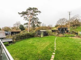 A garden with a tree, sheds, and a pathway at Pen Glorian in Conwy