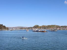 A kayak on water with boats and hills in the background at Pen Glorian in Conwy