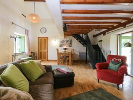 A living room with a sofa and dining area at Pen Glorian in Conwy