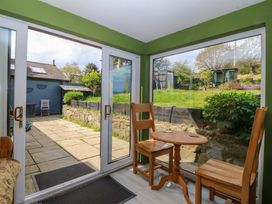 A conservatory with two chairs and a table overlooking a garden at Pen Glorian in Conwy