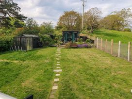 A garden with a path leading to a shed and flower bed at Pen Glorian in Conwy