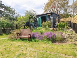 A garden with a wooden shed and bench at Pen Glorian in Conwy