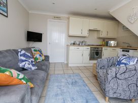 A living room with a sofa and kitchen area at Sea Spray in Bowleaze