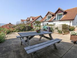 A garden with a table and benches at Sea Spray in Bowleaze