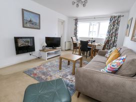 A living room with a sofa, television, and dining area at Flat 13, Chesil House, Bridport