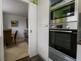 A kitchen with an oven and microwave visible from a hallway at Flat 13, Chesil House in Bridport