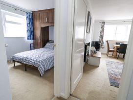 A bedroom with a bed and a doorway leading to a living area at Beachcombers, 13 Chesil House in Bridport