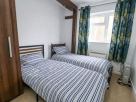 A bedroom with two single beds and a wardrobe at Beachcombers, 13 Chesil House in Bridport