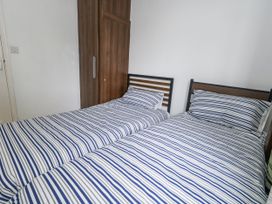 A bedroom with two beds and a wardrobe at Beachcombers, 13 Chesil House, Bridport