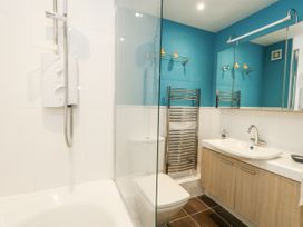 A bathroom featuring a shower, bathtub, toilet, and sink at Beachcombers, 13 Chesil House in Bridport