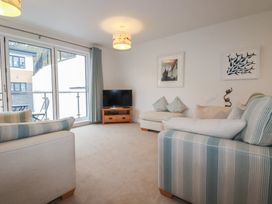 A living room with sofas a television on a wooden stand and sliding glass doors at 13 Clock Tower Court in Charlestown