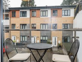 A balcony with a round metal table and two black chairs with white cushions overlooking modern townhouses at 13 Clock Tower Court in Charlestown