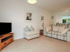 A living room with a striped sofa a TV on a wooden stand and two framed pictures on the wall at 13 Clock Tower Court in Charlestown