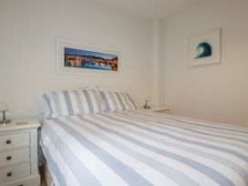A bedroom with a bed with striped bedding two bedside tables and framed artwork on the walls at 13 Clock Tower Court in Charlestown