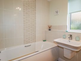 A bathroom with a bathtub a sink tiles on walls and a window at 13 Clock Tower Court Charlestown
