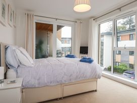 A bedroom with a bed, bedside table, TV, large windows, and a balcony at 13 Clock Tower Court in Charlestown