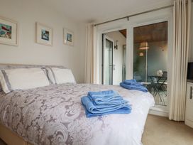 A bedroom with a bed covered in a patterned duvet and blue towels folded on top with framed pictures on the wall and a glass door leading to a balcony at 13 Clock Tower Court in Charlestown