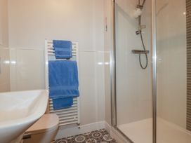 A bathroom with a sink a toilet a towel rack with blue towels and a shower enclosure at 13 Clock Tower Court in Charlestown