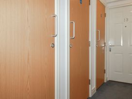 A hallway with three wooden doors and one white door with the number 13 at 13 Clock Tower Court in Charlestown
