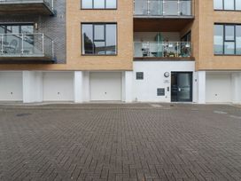 The exterior of a modern apartment building with multiple garage doors a glass entrance door and balconies above at 13 Clock Tower Court in Charlestown
