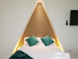 A bedroom with a bed against a wooden feature wall at Kingfisher House Saltburn-by-the-Sea