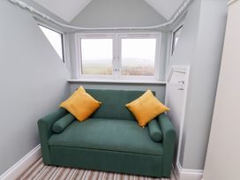 A snug with a green sofa and yellow cushions at Kingfisher House in Saltburn-by-the-Sea