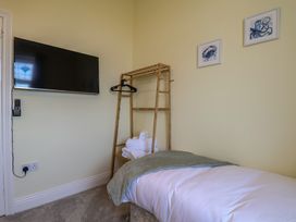 A bedroom with a bed, television, and clothes rack at Kingfisher House, Staithes