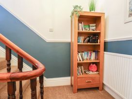 A bookshelf with books and a plant in a hallway at Kingfisher House in Staithes