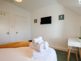 A bedroom with a television and towels on a bed at Kingfisher House in Staithes