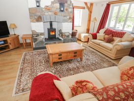 A living room with a stone fireplace wooden furniture beige sofas and red curtains at 5 Cart-Tws Bach in St Davids