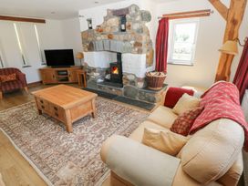 A living room with a stone fireplace wooden coffee table sofa and television at 5 Cart-Tws Bach in St Davids