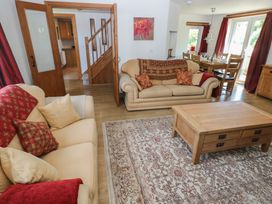 A living room with sofas a wooden coffee table a dining table and wooden doors at 5 Cart-Tws Bach in St Davids