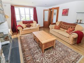 A living room with two beige sofas red cushions and a wooden coffee table at 5 Cart-Tws Bach in St Davids