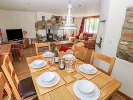 A dining table set with plates glasses and a wine bottle next to a living room with a stone fireplace and sofas at 5 Cart-Tws Bach in St Davids