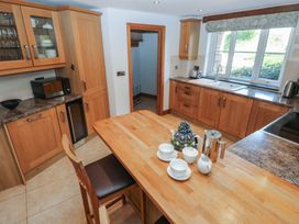 A kitchen with wooden cabinets and a wooden island with teacups and a teapot at 5 Cart-Tws Bach in St Davids