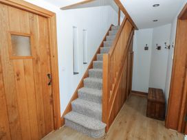 A hallway with wooden staircase carpeted steps wooden doors a wooden bench and coat hooks on the wall at 5 Cart-Tws Bach in St Davids